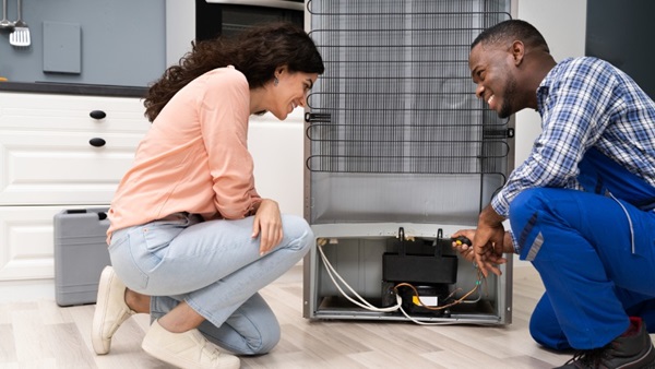 Un professionnel aide une femme à installer son frigo